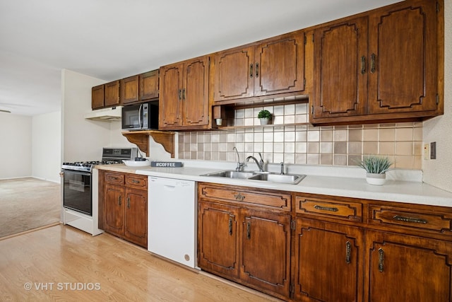 kitchen featuring a sink, range with gas cooktop, white dishwasher, black microwave, and light countertops