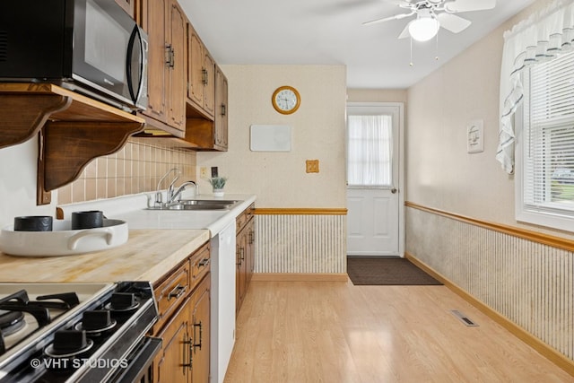 kitchen featuring a sink, black microwave, light wood-style flooring, light countertops, and visible vents
