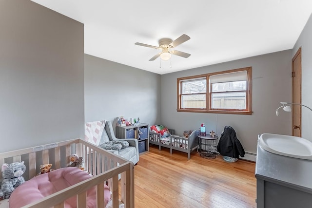 5626 S Nashville Ave, Chicago, IL 60638 - bedroom with a nursery area, a baseboard radiator, light wood-type flooring, and ceiling fan