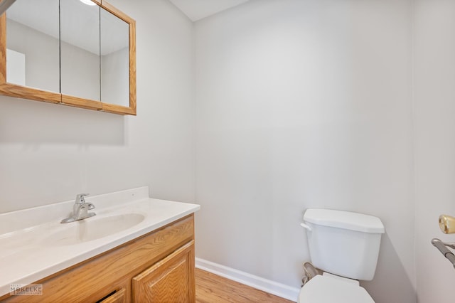 bathroom featuring baseboards, toilet, vanity, and wood finished floors