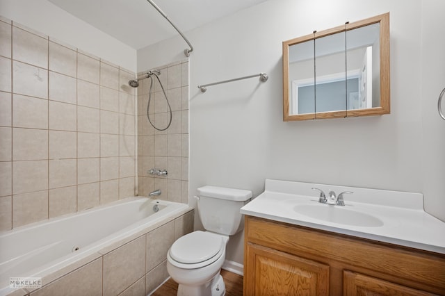 bathroom with toilet, vanity, and tiled shower / bath