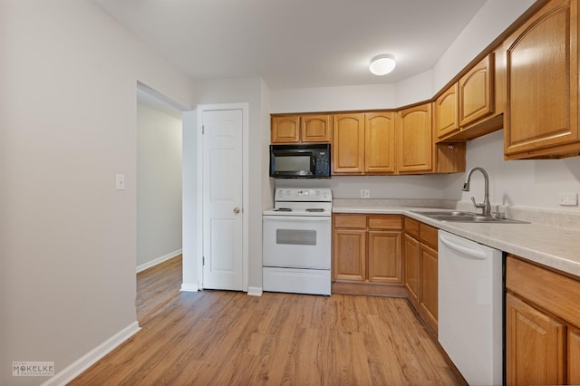 kitchen featuring a sink, light wood-type flooring, baseboards, white appliances, and light countertops