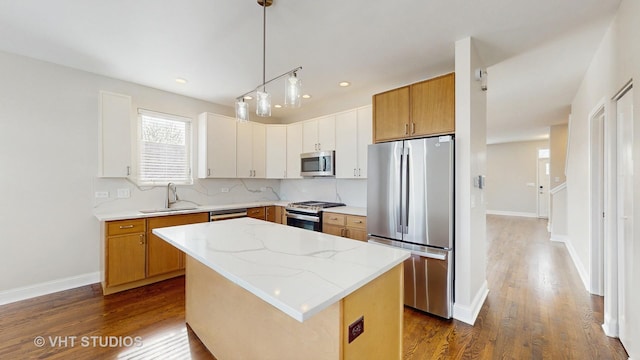 kitchen with a kitchen island, dark wood-style flooring, hanging light fixtures, a sink, and stainless steel appliances