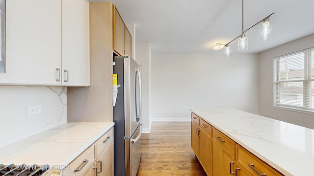 kitchen with freestanding refrigerator, decorative light fixtures, light wood-style flooring, and light stone countertops