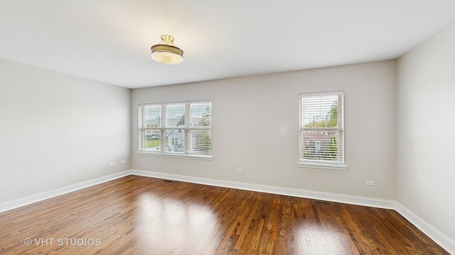 unfurnished room with baseboards, a healthy amount of sunlight, and wood finished floors