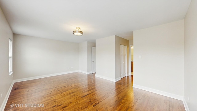 unfurnished room with baseboards, wood finished floors, and visible vents