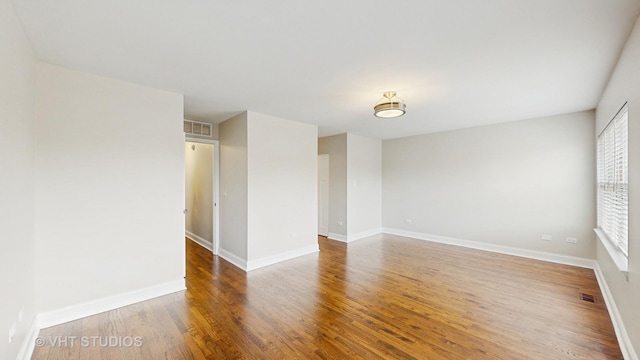 spare room with baseboards, visible vents, and wood finished floors