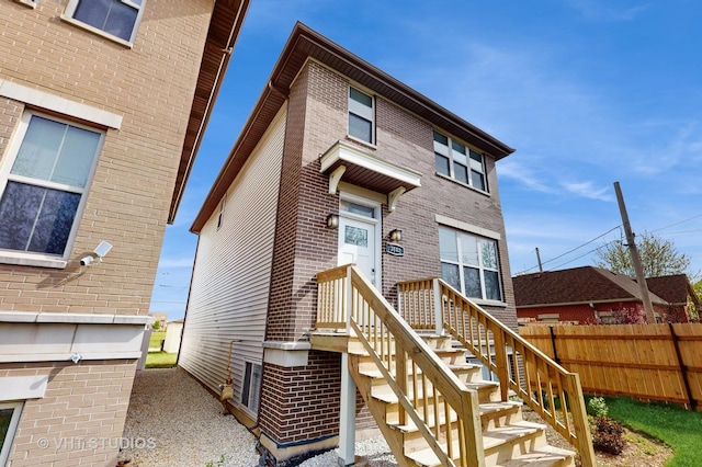 back of house featuring brick siding and fence