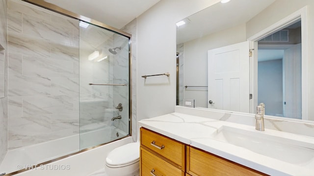 full bath featuring toilet, visible vents, combined bath / shower with glass door, and vanity