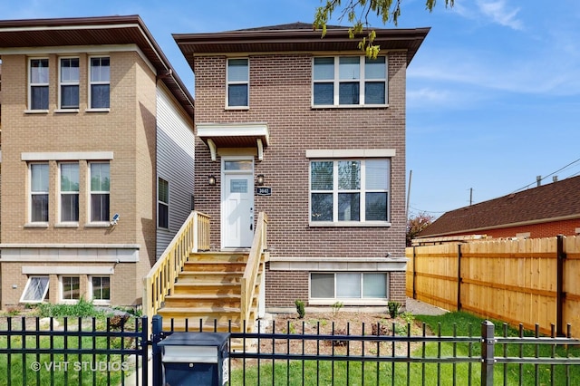 view of front of house with brick siding, a fenced backyard, and a front lawn