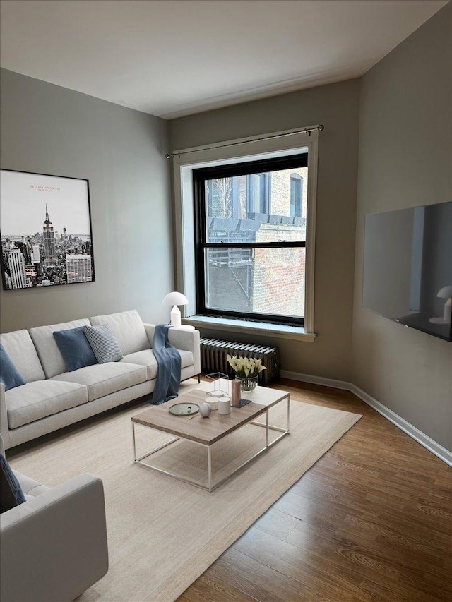 living area featuring radiator heating unit, wood finished floors, and baseboards