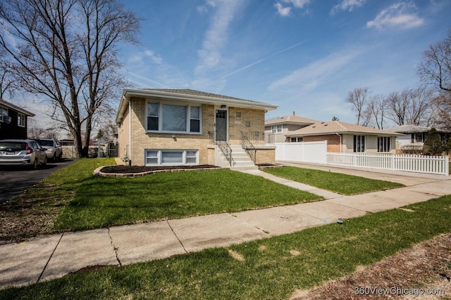 view of front facade featuring brick siding, fence, and a front yard