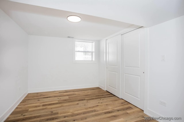below grade area with wood finished floors, visible vents, and baseboards