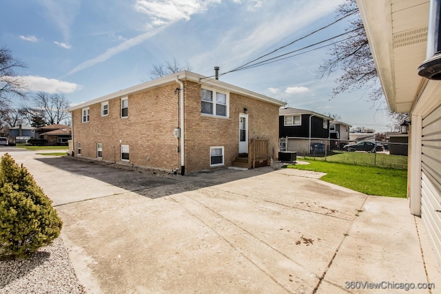 view of home's exterior with central AC unit, fence, a yard, a patio area, and brick siding