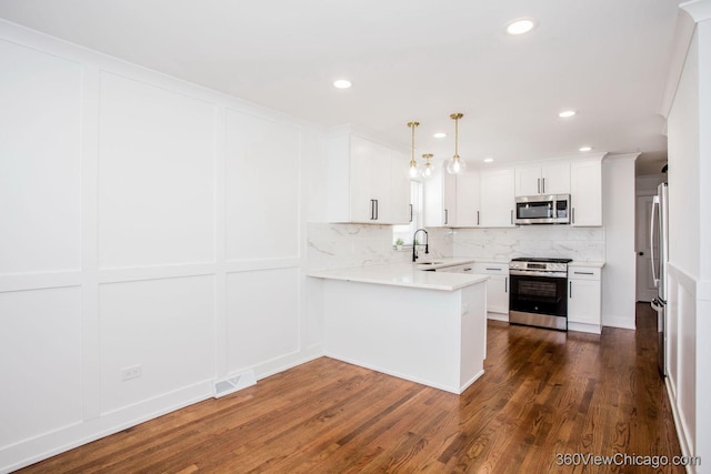 kitchen featuring stainless steel appliances, backsplash, visible vents, a sink, and a peninsula
