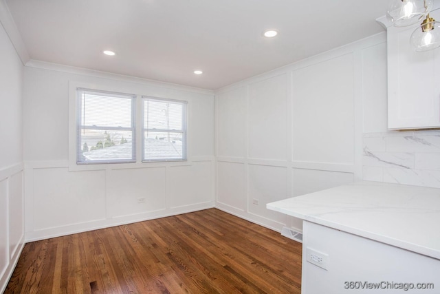unfurnished room with a decorative wall, ornamental molding, dark wood-style flooring, and visible vents