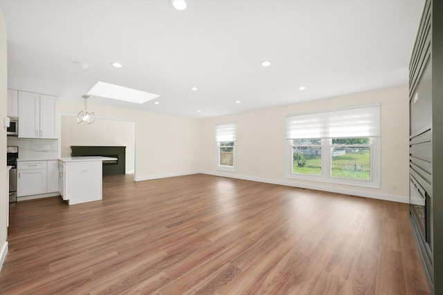 1 Fernwood Ct, Romeoville, IL 60446 - unfurnished living room with a fireplace, a skylight, light wood finished floors, baseboards, and recessed lighting