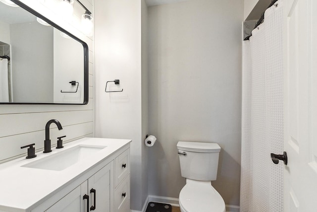 bathroom with toilet, baseboards, and vanity