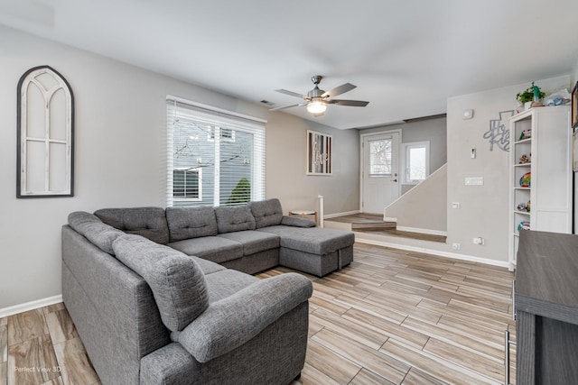 living room featuring light wood finished floors, a ceiling fan, baseboards, and visible vents