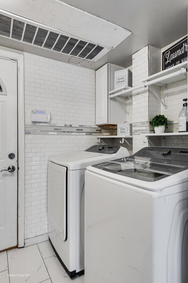 laundry room with marble finish floor, washing machine and clothes dryer, and cabinet space