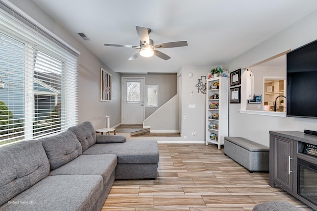 living area with baseboards, a ceiling fan, visible vents, and light wood-style flooring