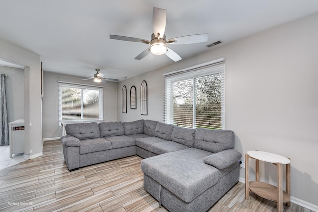 living area with baseboards, a ceiling fan, light wood-style floors, and visible vents