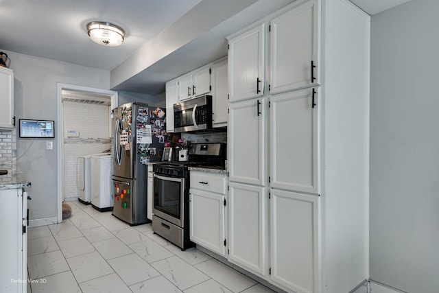 kitchen with white cabinets, marble finish floor, washing machine and dryer, appliances with stainless steel finishes, and light stone countertops