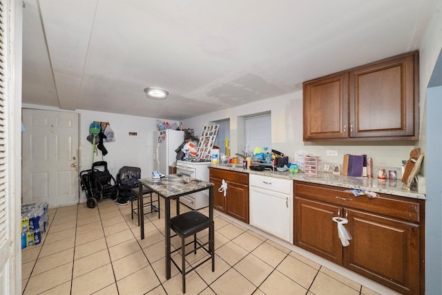 3047 S Millard Ave, Chicago, IL 60623 - kitchen with light stone counters, a sink, brown cabinets, light tile patterned floors, and freestanding refrigerator