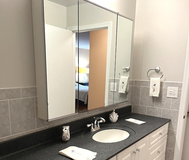 ensuite bathroom with ensuite bath, vanity, and tile walls