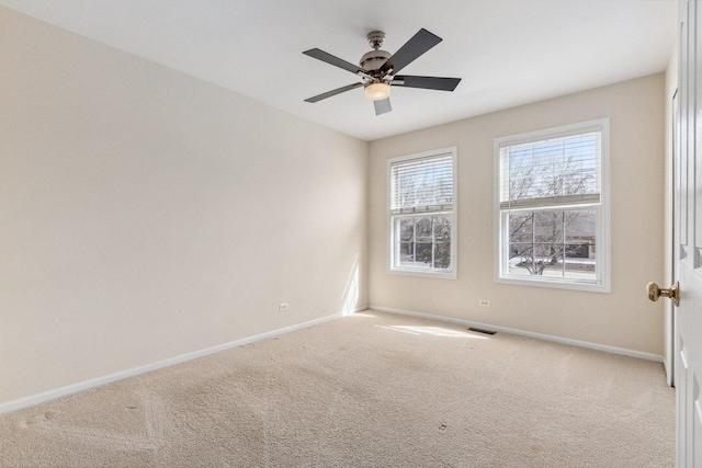 carpeted spare room with visible vents, baseboards, and a ceiling fan