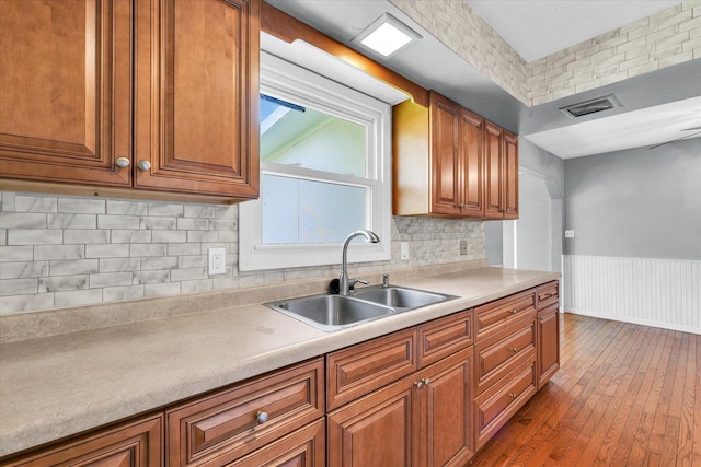 2240 Marilyn Dr, Saint Joseph, IL 61873 - kitchen featuring a sink, dark wood-type flooring, brown cabinetry, light countertops, and a wainscoted wall