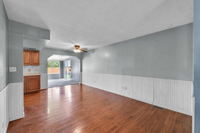 2240 Marilyn Dr, Saint Joseph, IL 61873 - unfurnished living room featuring a ceiling fan, a textured ceiling, hardwood / wood-style flooring, and a wainscoted wall