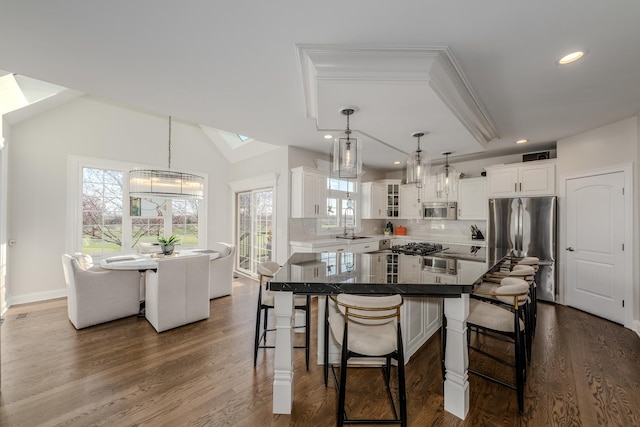 kitchen featuring a skylight, glass insert cabinets, stainless steel appliances, white cabinetry, and a notable chandelier