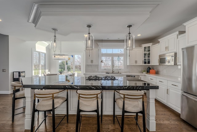 kitchen with white cabinets, backsplash, a kitchen island, appliances with stainless steel finishes, and a breakfast bar area