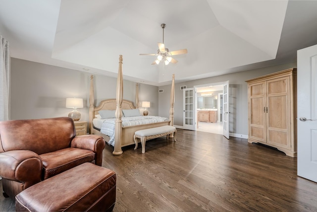 bedroom with a tray ceiling, dark wood finished floors, and baseboards