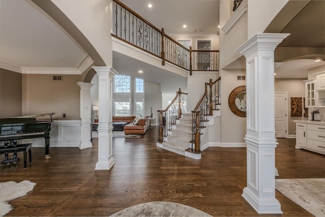 foyer entrance with crown molding, visible vents, and decorative columns
