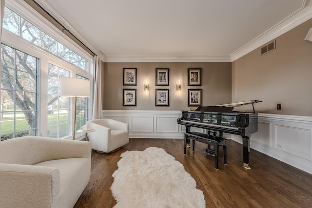 sitting room with wainscoting, dark wood-style flooring, ornamental molding, and visible vents