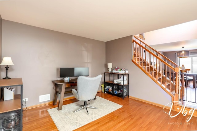 office space with baseboards, visible vents, and wood finished floors