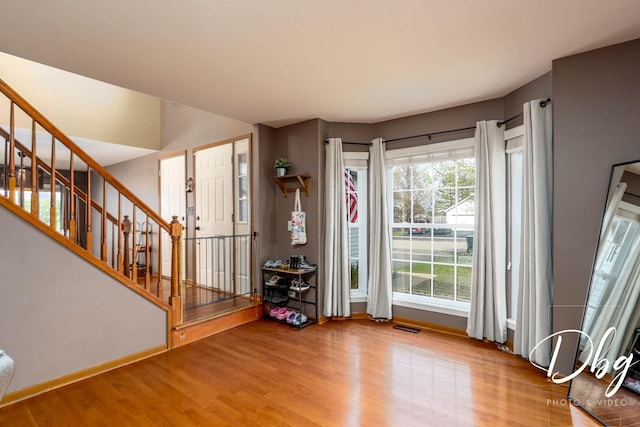 entryway featuring stairway, baseboards, wood finished floors, and visible vents