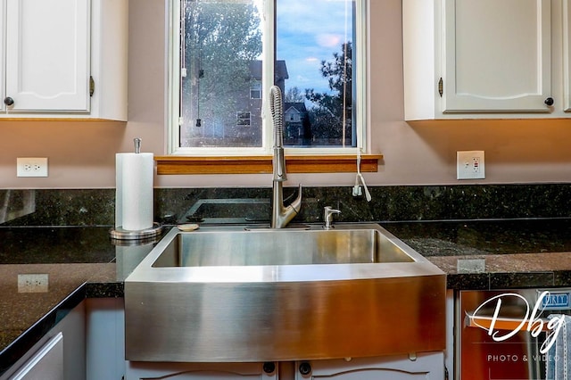 interior details featuring a sink, white cabinetry, and dark countertops