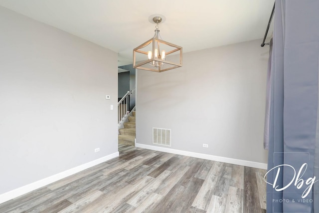 2272 Iroquois Ln, Round Lake Heights, IL 60073 - unfurnished dining area with visible vents, wood finished floors, baseboards, a notable chandelier, and stairs