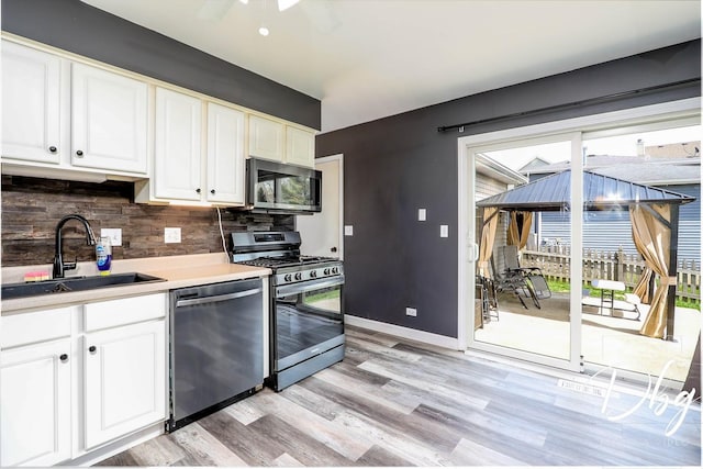 2272 Iroquois Ln, Round Lake Heights, IL 60073 - kitchen with light wood-type flooring, white cabinets, tasteful backsplash, a sink, and stainless steel appliances