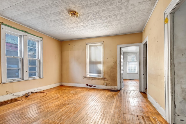 empty room featuring wood-type flooring, baseboards, and visible vents