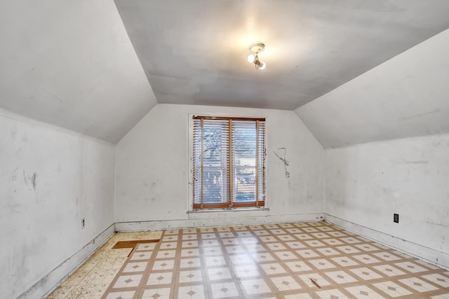 bonus room with light floors and vaulted ceiling