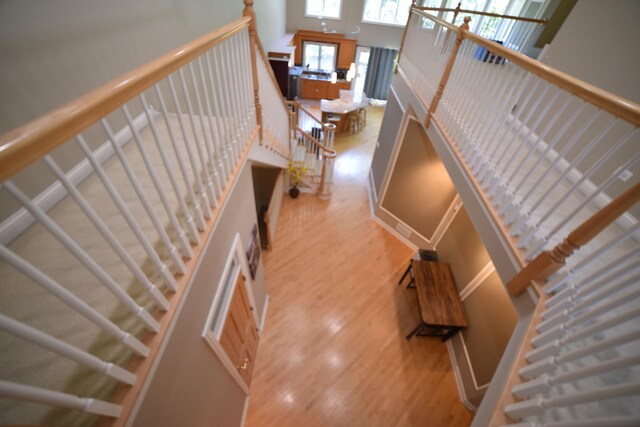 living area featuring a towering ceiling, light wood-style floors, and a high end fireplace