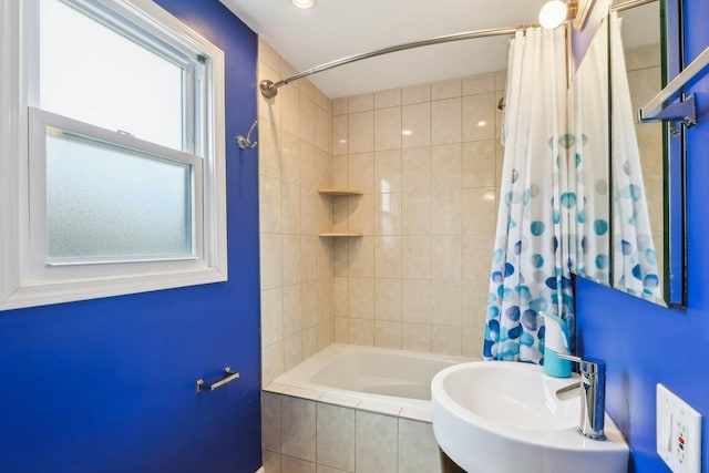 bathroom with tiled shower / bath combo and a sink