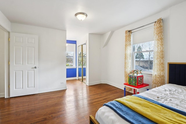 bedroom with baseboards, wood finished floors, and multiple windows