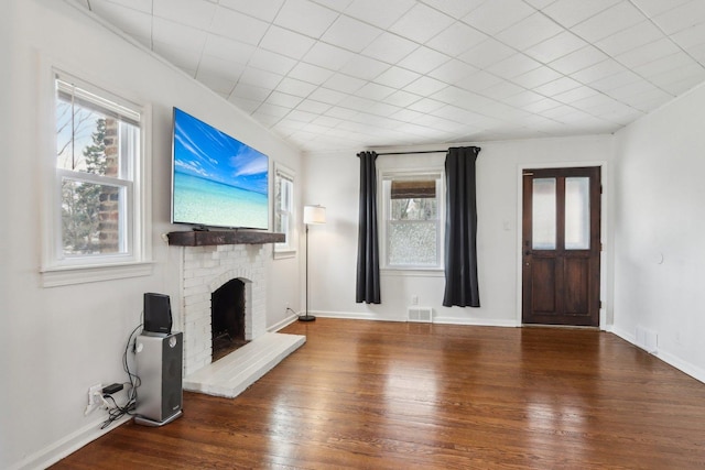 unfurnished living room featuring visible vents, wood finished floors, and plenty of natural light