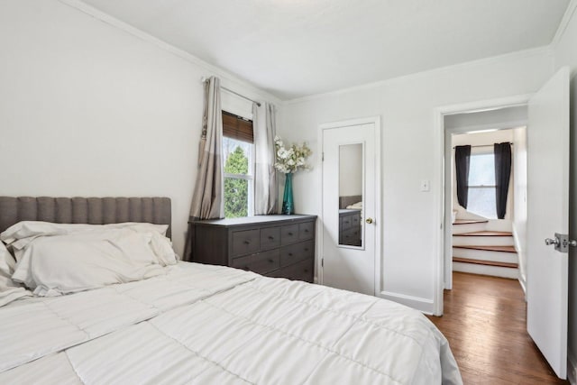 bedroom with wood finished floors and crown molding