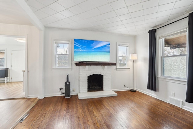 unfurnished living room featuring a fireplace, visible vents, plenty of natural light, and hardwood / wood-style floors